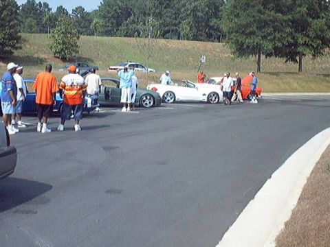1998 Ford Taurus - Several vehicles and a group of people are gathered in an outdoor lot, possibly at a car show.
