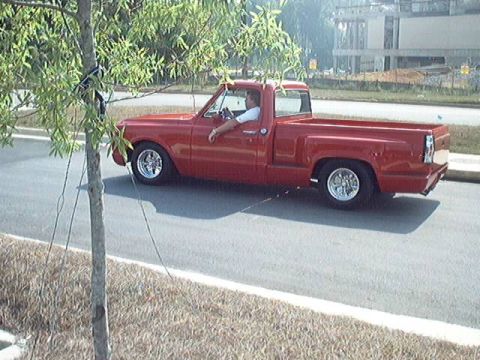 1998 Ford Taurus - A red pickup truck with custom chrome wheels is seen driving down a road.