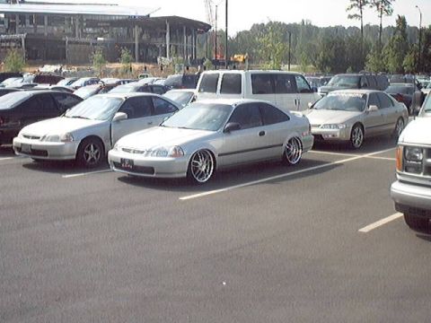 1998 Ford Taurus - Silver coupe with aftermarket wheels is parked in a lot with other vehicles.