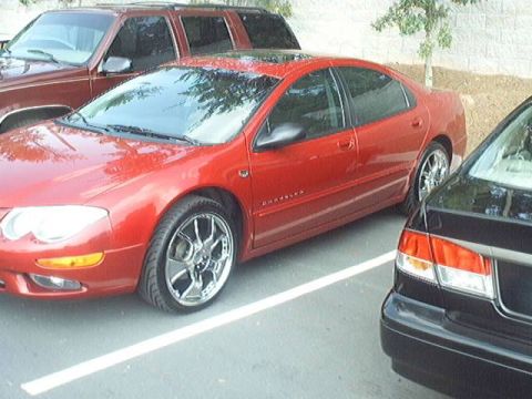 1998 Ford Taurus - A red Chrysler sedan is parked in a lot with other vehicles.