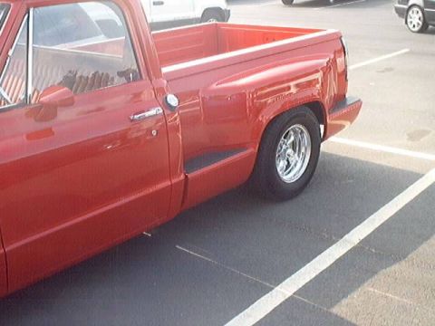 1998 Ford Taurus - A red pickup truck is parked in a lot next to other vehicles.