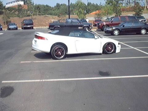 1998 Ford Taurus - Several cars are parked in a lot, including a white convertible sports car in the foreground.