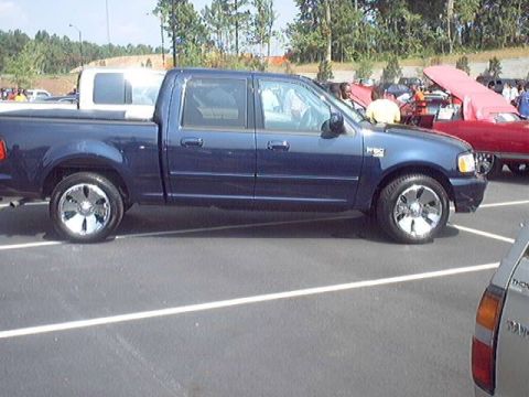 1998 Ford Taurus - A blue pickup truck is parked in a lot with other vehicles visible in the background.