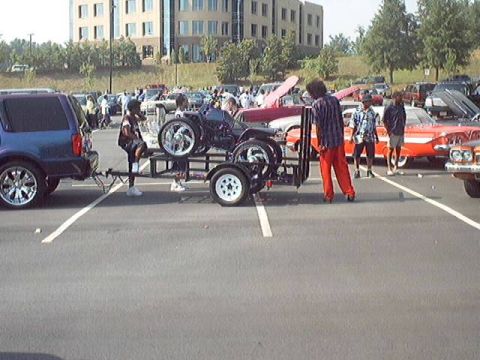 1998 Ford Taurus - Custom trike being towed by a blue SUV at an outdoor car show event.