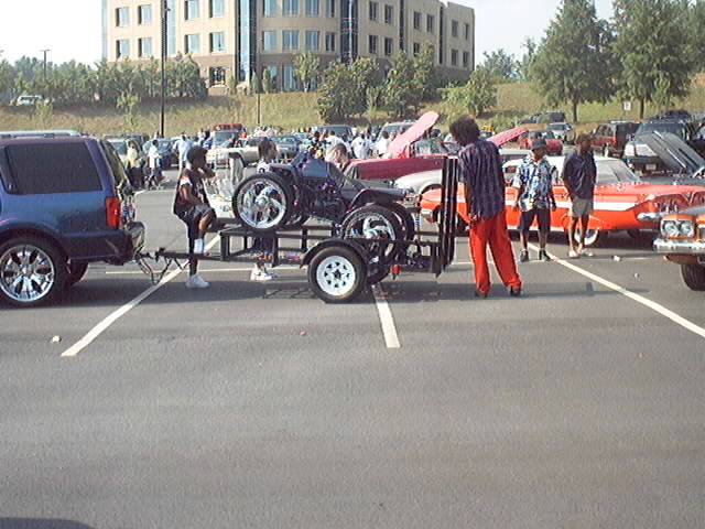 Two custom ATVs on chrome wheels loaded on a trailer behind a blue SUV