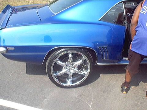 1998 Ford Taurus - Side view of a blue classic car with custom chrome wheels and a spoiler.