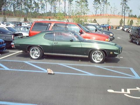 1998 Ford Taurus - A green classic coupe is parked in a lot with other vehicles.