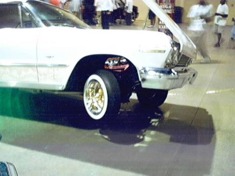 1998 Ford Taurus - Customized classic car with chrome details and gold wire wheels on display.