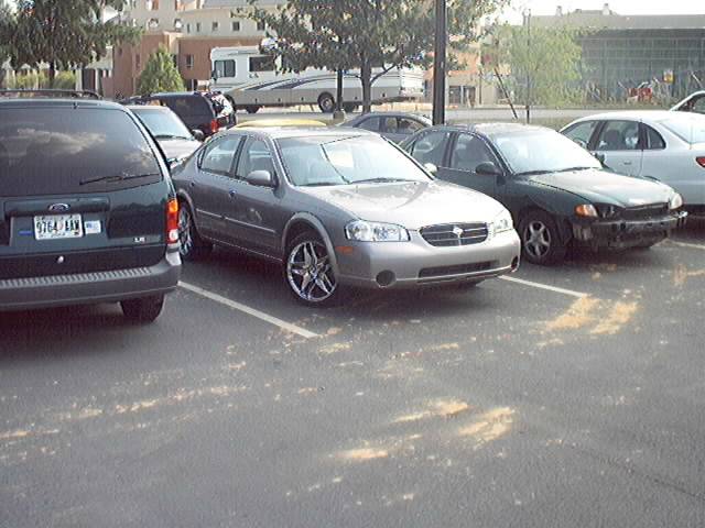 Silver sedan with custom rims parked in a lot, front quarter view
