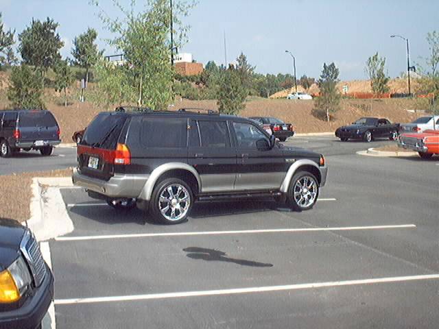 Black Mitsubishi Montero Sport SUV parked in a lot, with other vehicles visible