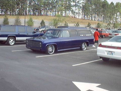 1998 Ford Taurus - A dark blue extended cab pickup truck is parked in a lot next to other vehicles.