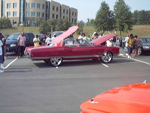 1998 Ford Taurus - A classic red convertible with its top up and hoods open is displayed at an outdoor car show.