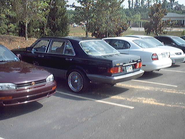 Dark sedan with wire wheels parked in a lot