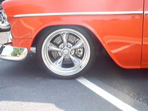 1998 Ford Taurus - Close-up of an orange car's side, showing a chrome wheel and part of the fender.