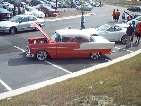 1998 Ford Taurus - A classic 1955 Chevrolet Bel Air, painted in red and white, is displayed with its hood open at a car show.
