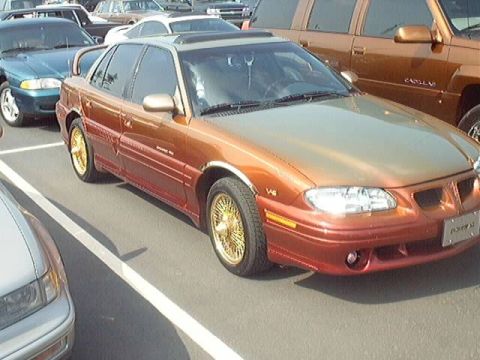 1998 Ford Taurus - This sedan features a striking two-tone paint job in orange and gold, complemented by gold wire wheels.