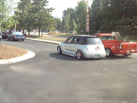 1998 Ford Taurus - A silver PT Cruiser and a red pickup truck are seen parked on a street.