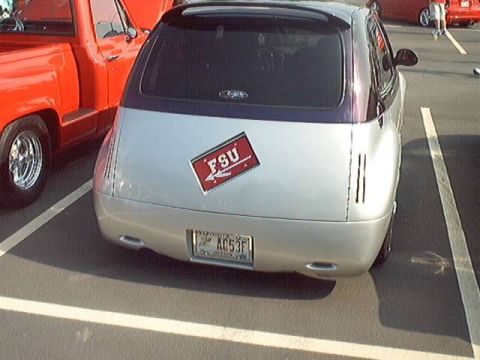 1998 Ford Taurus - A silver car with a distinctive purple stripe and an FSU sticker is parked next to a red pickup truck.