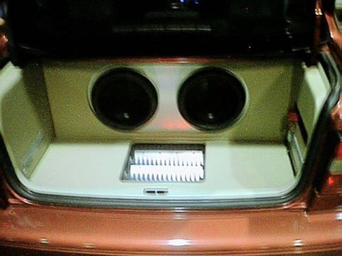1998 Ford Taurus - The trunk of a car is open, revealing a custom enclosure with two subwoofers and a white component.