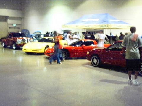 1998 Ford Taurus - Several sports cars are on display at an indoor car show, including a red convertible and a yellow model.