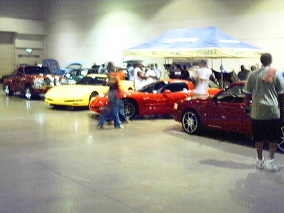Yellow and red Corvettes and a red convertible on display at an indoor car show