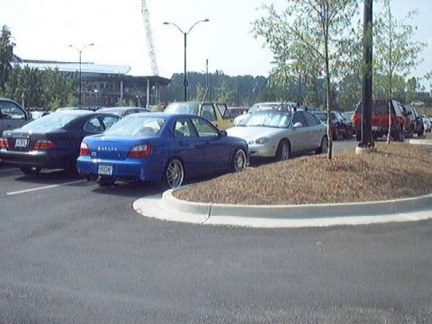 1998 Ford Taurus - A blue Subaru WRX is seen from the rear in a parking lot with several other vehicles.