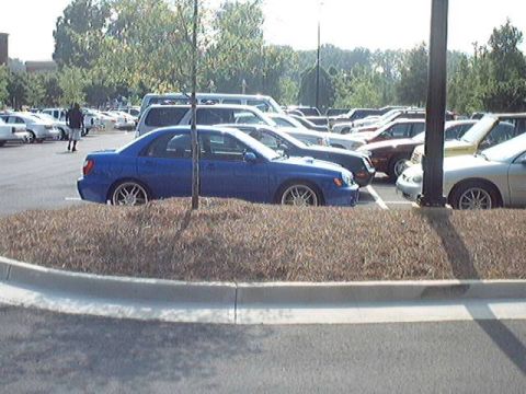 1998 Ford Taurus - A blue Subaru Impreza WRX is parked in a lot with several other vehicles visible.