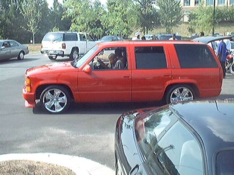 1998 Ford Taurus - A red SUV is seen from the side, with other vehicles in the background.