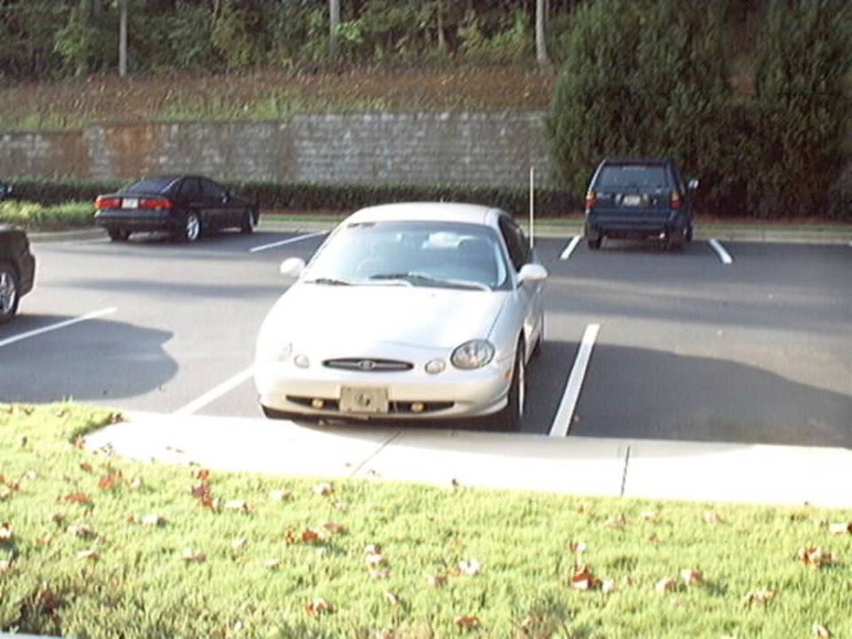 Front view of a silver Ford Taurus sedan parked nose-out in a parking lot