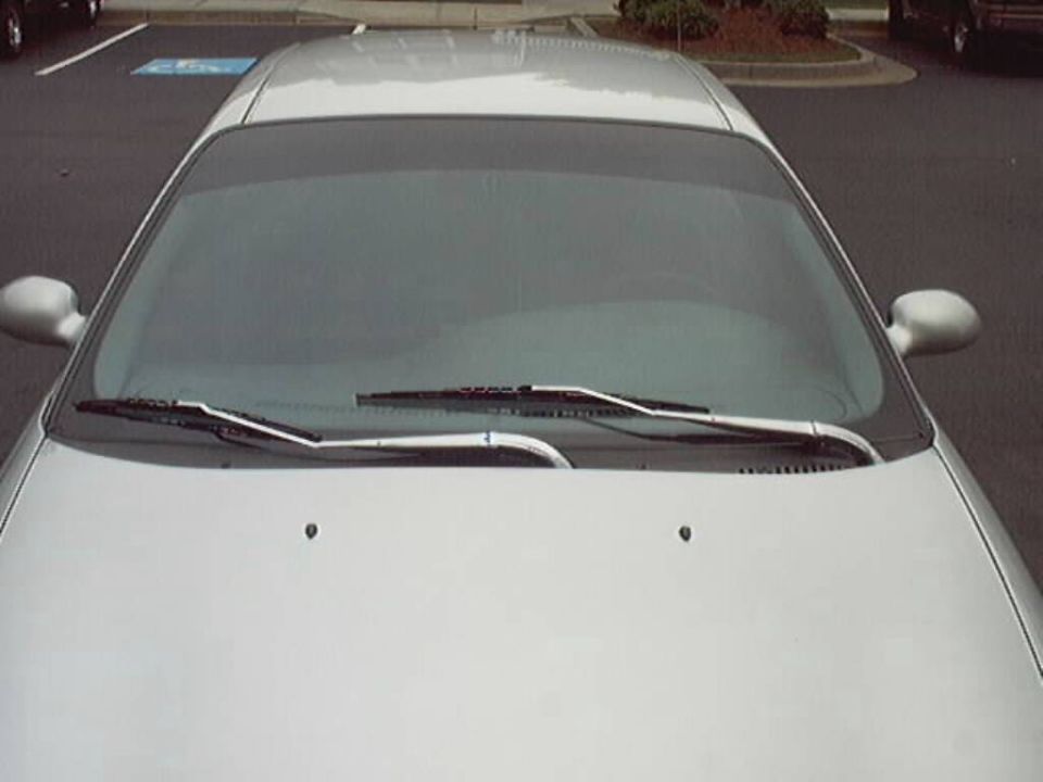 Overhead view of a silver sedan hood and windshield with chrome wiper arms