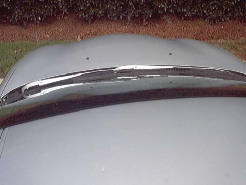 1998 Ford Taurus - Close-up looking down the front of a silver-gray sedan hood at a chrome bumper or trim bar spanning the nose, with two small holes in the h…
