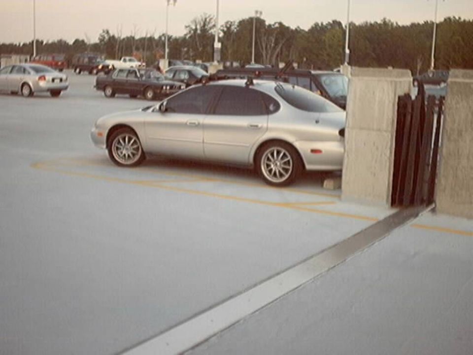 Silver Ford Taurus sedan in profile on a parking garage roof deck