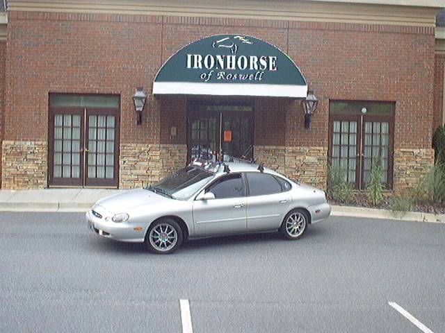 Silver Ford Taurus sedan parked outside the brick Ironhorse of Roswell building