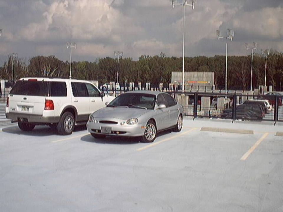 Silver Ford Taurus sedan parked next to a white Ford Explorer on a rooftop lot
