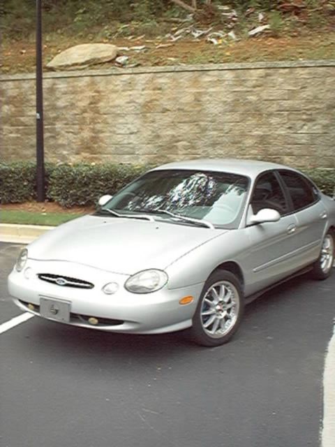 1998 Ford Taurus - A silver 1998 Ford Taurus is parked in a lot, showing its front 3/4 view.