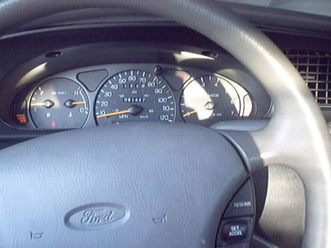 1998 Ford Taurus - Close-up of a Ford instrument cluster seen through the steering wheel, showing a 120 MPH speedometer with an odometer reading around 091487…