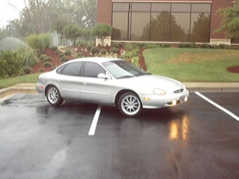 1998 Ford Taurus - Silver 1998 Ford Taurus in a parking lot during a light rain.