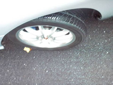 1998 Ford Taurus - A close-up view of a car's wheel and fender shows a yellow leaf on the asphalt.