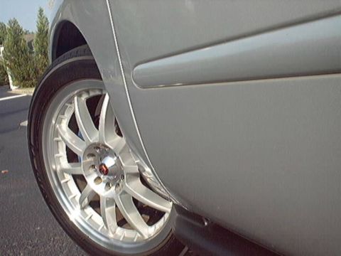 1998 Ford Taurus - Silver car side panel and wheel detail, showing aftermarket rims.