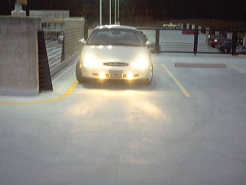 1998 Ford Taurus - A silver sedan is parked in a lot at night, its headlights illuminating the ground.