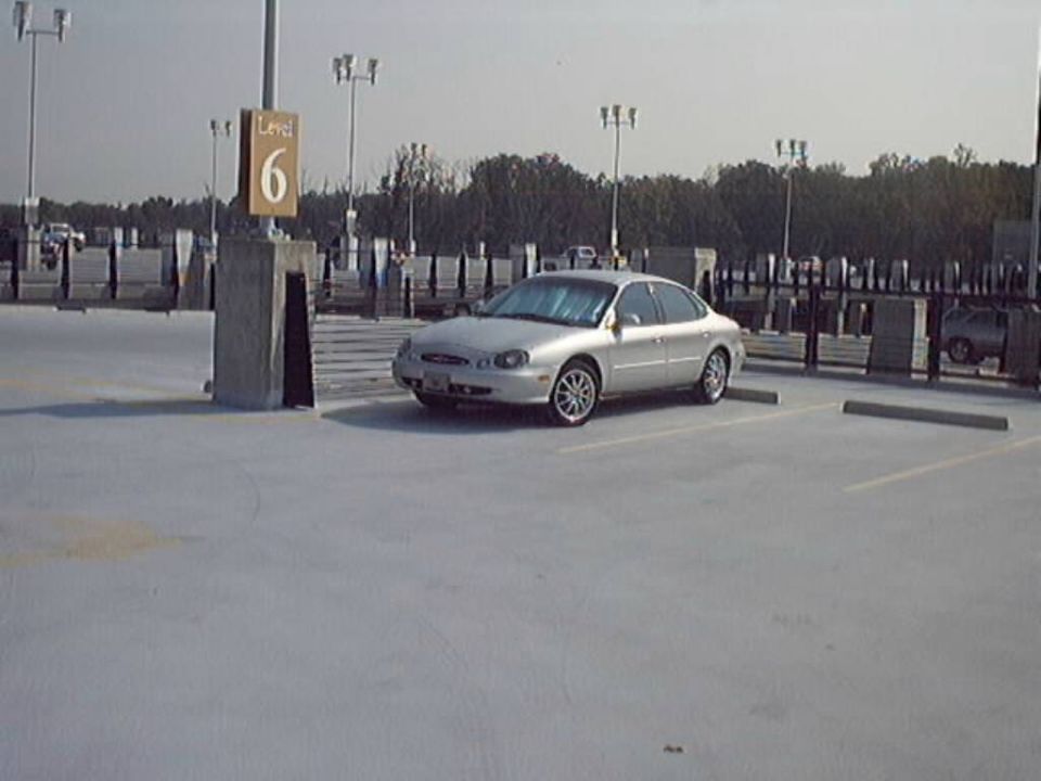 Silver 1998 Ford Taurus sedan parked in a concrete parking garage, 3/4 front view
