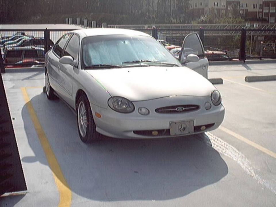 Silver 1998 Ford Taurus parked in a lot, driver's door open