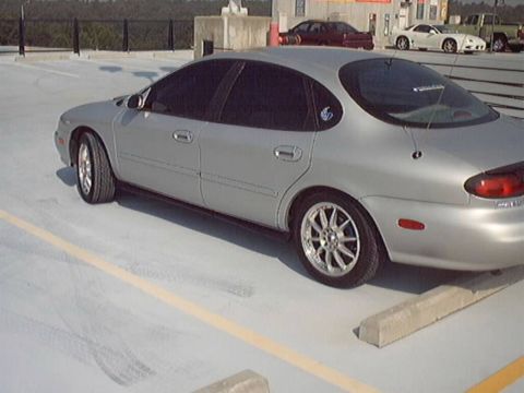 1998 Ford Taurus - Silver Mercury Sable sedan on alloy wheels parked on a concrete rooftop parking deck.