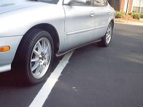 1998 Ford Taurus - This silver sedan features custom wheels and side running boards, suggesting a model year around 2000.