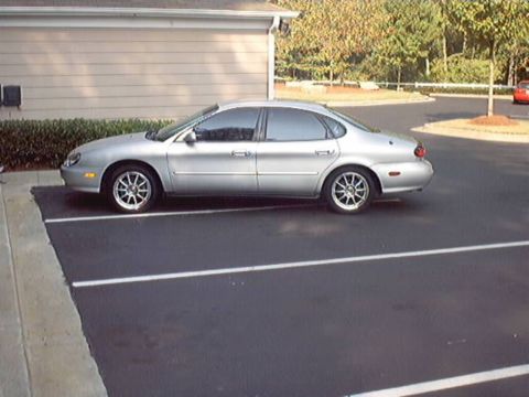 1998 Ford Taurus - This silver 1998 Ford Taurus is parked in a lot, showing its side profile.
