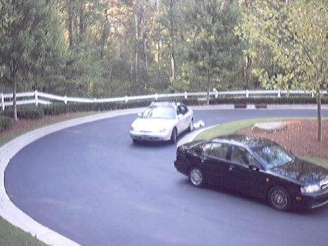 1998 Ford Taurus - Two sedans parked on a curving asphalt drive lined with a white split-rail fence and trees: a silver Ford Taurus at left seen from the fron…