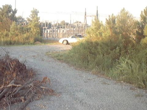 1998 Ford Taurus - White sedan parked on gravel road with power station in background.