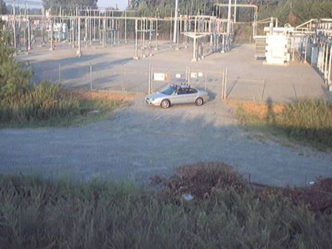 1998 Ford Taurus - A silver sedan is parked inside a fenced area of an electrical substation.