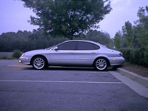 1998 Ford Taurus - Silver Ford Taurus four-door sedan photographed in profile at dusk in an empty parking lot, with tinted windows, multi-spoke alloy wheels a…