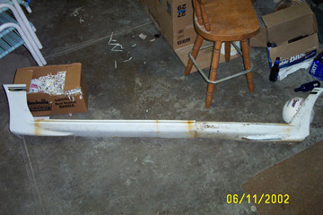 1993 Ford Taurus - A detached white car bumper is shown on the floor, with various boxes and a stool in the background.